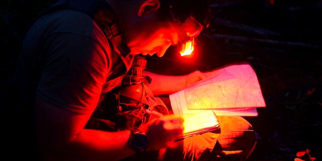 A soldier from the U.S. Army John F. Kennedy Special Warfare Center and School plots his next movement while completing the Special Forces Assessment and Selection night land navigation course near Hoffman, N.C., on May 7, 2019. (Ken Kassens/U.S. Army via AP)