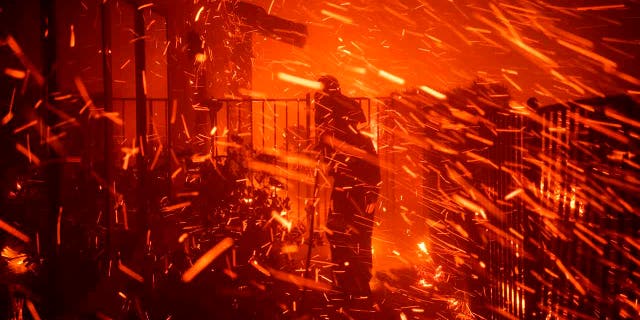 Jerry Rowe uses a garden hose to save his home on Beaufait Avenue from the Saddleridge fire in Granada Hills, Calif., Friday, Oct. 11, 2019. (AP Photo/Michael Owen Baker)