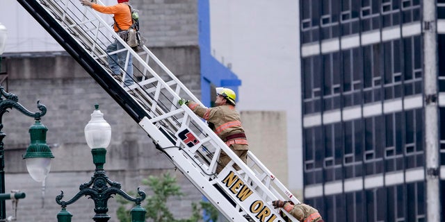 A rescued worker, left, and a firefighter look back at the damaged building after a large portion of a hotel under construction suddenly collapsed in New Orleans on Saturday. (Scott Threlkeld/The Advocate via AP)