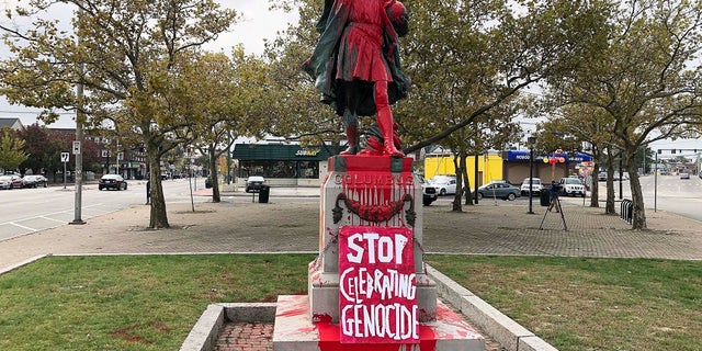 A sign reading "stop celebrating genocide" sits at the base of a statue of Christopher Columbus on Monday in Providence, Rhode Island, after it was vandalized with red paint on the day named to honor him as one of the first Europeans to reach the New World. (AP Photo/Michelle R. Smith)