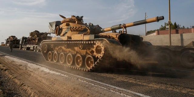 A Turkish forces tank is driven to its new position after was transported by trucks, on a road towards the border with Syria in Sanliurfa province, Turkey, on Monday, Oct. 14, 2019. Syrian troops entered several northern towns and villages Monday, getting close to the Turkish border as Turkey's army and opposition forces backed by Ankara marched south in the same direction, raising concerns of a clash between the two sides as Turkey's invasion of northern Syria entered its sixth day. (AP Photo/Emrah Gurel)