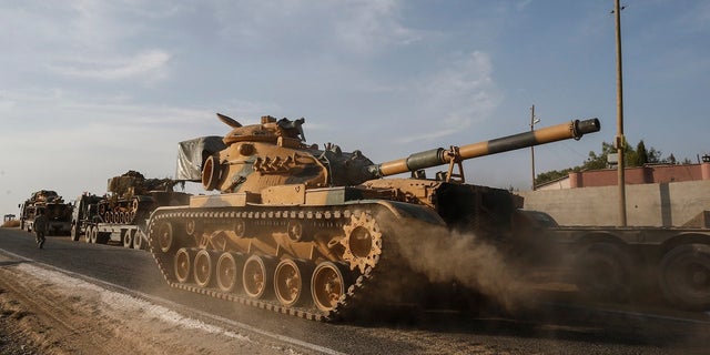 A Turkish forces tank is driven to its new position after was transported by trucks, on a road towards the border with Syria in Sanliurfa province, Turkey, on Monday, Oct. 14, 2019. Syrian troops entered several northern towns and villages Monday, getting close to the Turkish border as Turkey's army and opposition forces backed by Ankara marched south in the same direction, raising concerns of a clash between the two sides as Turkey's invasion of northern Syria entered its sixth day. (AP Photo/Emrah Gurel)