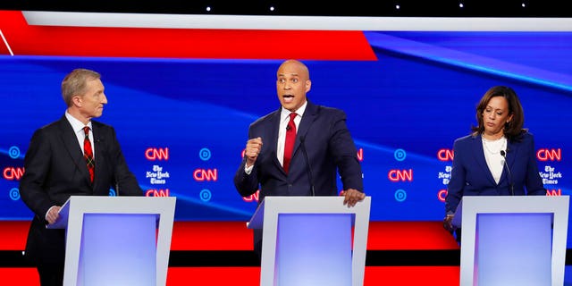 Democratic presidential candidate businessman Tom Steyer, left, and Sen. Kamala Harris, D-Calif., right, listen as Sen. Cory Booker, D-N.J., speaks during a Democratic presidential primary debate hosted by CNN/New York Times at Otterbein University, Tuesday, Oct. 15, 2019, in Westerville, Ohio. (AP Photo/John Minchillo)