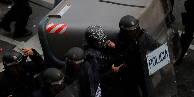 A police officer's helmet is covered with paint as officers take position on the fifth day of protests over the conviction of a dozen Catalan independence leaders in Barcelona, Spain, Friday, Oct. 18, 2019. (AP Photo/Manu Fernandez)