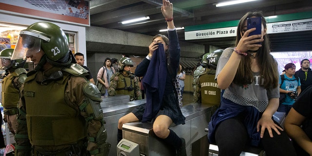 Chile's Carabineros stand next to students blocking the turnstile to the subway protesting against the rising cost of subway and bus fare, in Santiago, Friday, Oct. 18, 2019. (Associated Press)