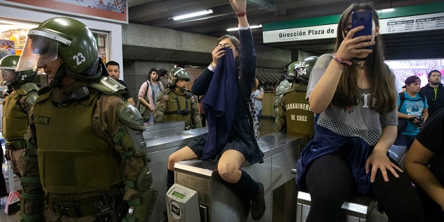 Chile's Carabineros stand next to students blocking the turnstile to the subway protesting against the rising cost of subway and bus fare, in Santiago, Friday, Oct. 18, 2019. (Associated Press)