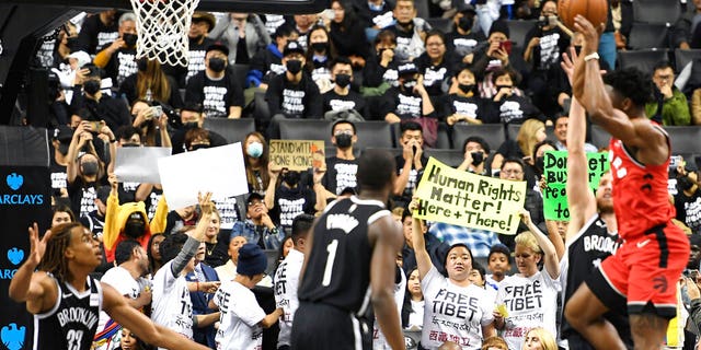 People raise signs referencing Tibet and Hong Kong during the fourth quarter of a preseason NBA basketball game between the Toronto Raptors and the Brooklyn Nets, Friday, Oct. 18, 2019, in New York. 