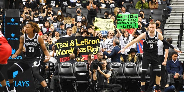 People raise signs referencing Tibet and Hong Kong during the fourth quarter of a preseason NBA basketball game between the Toronto Raptors and the Brooklyn Nets, Friday, Oct. 18, 2019, in New York. (AP Photo/Sarah Stier)