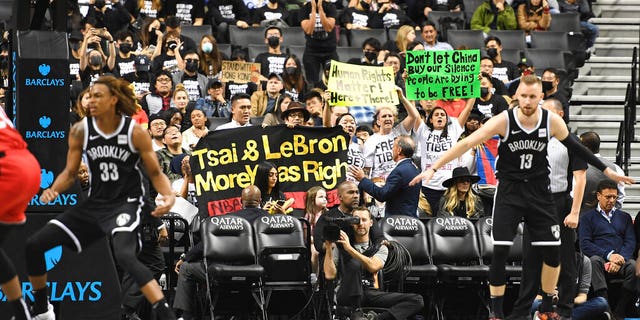 People raise signs referencing Tibet and Hong Kong during the fourth quarter of a preseason NBA basketball game between the Toronto Raptors and the Brooklyn Nets, Friday, Oct. 18, 2019, in New York. (AP Photo/Sarah Stier)