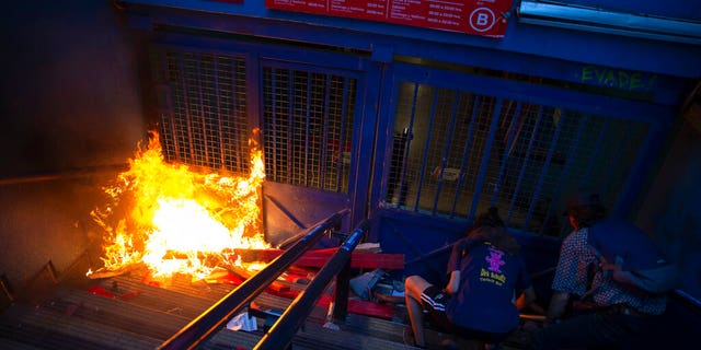 Protesters push a bicycle in front of a gate of the Santa Lucia subway station during a protest against the rising cost of subway and bus fares, in Santiago, Friday, Oct. 18, 2019.