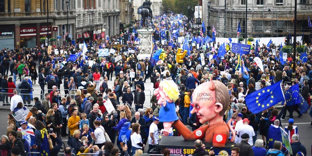 An effigy of Dominic Cummings advisor to British Prime Minister Boris Johnson, holds an effigy of Prime Minister Johnson, right, during a protest march in London, Saturday, Oct. 19, 2019. 