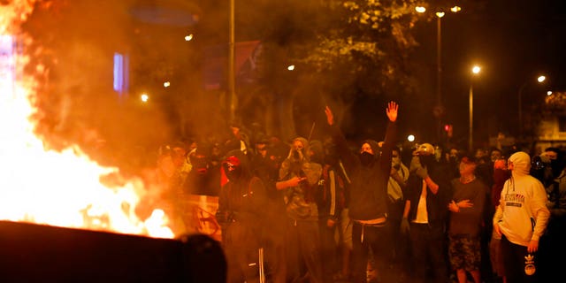 Protestors stand by a burning barricade in Barcelona, Spain, Saturday, Oct. 19, 2019. Radical separatists have clashed with police each night in Barcelona and other Catalan cities following huge peaceful protests of people angered by Monday's Supreme Court verdict that sentenced nine separatist leaders to prison. (AP Photo/Emilio Morenatti)