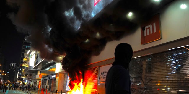 Protesters set fire to a Xiaomi shop at Nathan road in Hong Kong, Sunday, Oct. 20, 2019. Hong Kong protesters again flooded streets on Sunday, ignoring a police ban on the rally and setting up barricades amid tear gas and firebombs. (AP Photo/Vincent Yu)