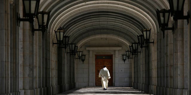 In this photo taken on Monday, Oct. 14, 2019, A friar walks next to The Valley of the Fallen mausoleum near El Escorial, outskirts of Madrid.