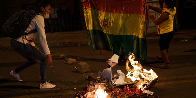 Supporters of opposition presidential candidate Carlos Mesa burn campaign posters of ruling party congressional candidates outside the Supreme Electoral Court where election ballots are being counted in La Paz, Bolivia, Monday, Oct. 21, 2019.