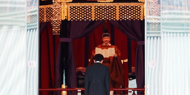 Japan's Emperor Naruhito speaks as Prime Minister Shinzo Abe bows during a ceremony to proclaim his enthronement to the world, called Sokuirei-Seiden-no-gi, at the Imperial Palace in Tokyo, Japan, Tuesday, Oct. 22, 2019. (Issei Kato/Pool Photo via AP)