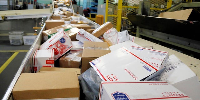 In this Dec. 14, 2017, file photo, packages travel on a conveyor belt for sorting at the main post office in Omaha, Neb. The city of New York and the state of California sued the U.S. Postal Service Tuesday, Oct. 22, 2019, to stop tens of thousands of cigarette packages from being mailed from foreign countries to U.S. residents, saying the smugglers are engaging in “cigarette tax evasion” while postal workers look the other way. (AP Photo/Nati Harnik, File)