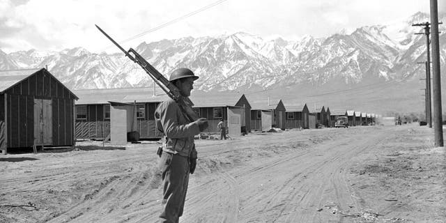 In this May 23, 1943, file photo, an American soldier guards a Japanese internment camp at Manzanar, Calif.