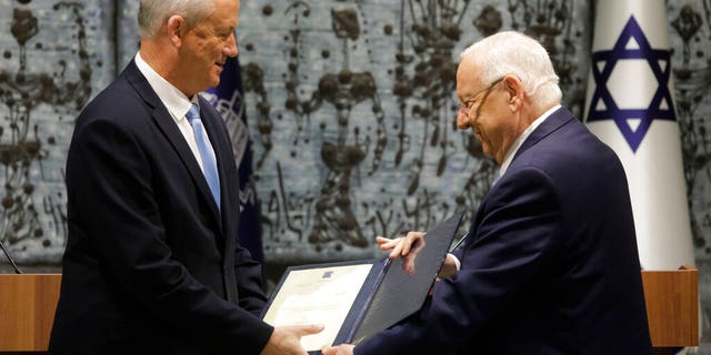 Israeli President Reuven Rivlin, right, hands a mandate to form new government to Blue and White Party leader Benny Gantz in Jerusalem, Wednesday, Oct. 23, 2019.