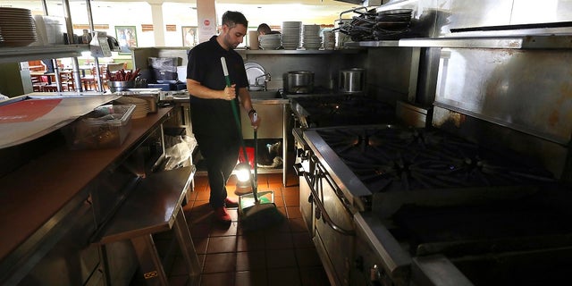 A power shutoff earlier this month leaves Salvador Espinosa with little to do but sweep up at Mary's Pizza Shack in Santa Rosa, Calif.