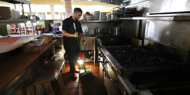 A power shutoff earlier this month leaves Salvador Espinosa with little to do but sweep up at Mary's Pizza Shack in Santa Rosa, Calif.