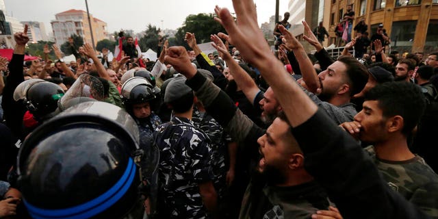 Lebanese riot policemen separates between anti-government protesters, left, and Hezbollah supporters, right during a protest in Beirut, Lebanon, Thursday, Oct. 24, 2019.