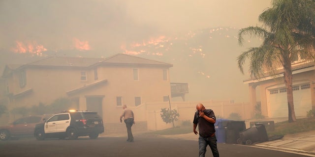 A resident covers his face as a wildfire approaches on Thursday in Santa Clarita, Calif. (AP Photo/Marcio Jose Sanchez)