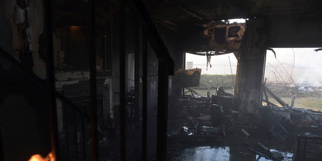 A burnt house lays flooded as leftover flames from the Tick Fire continue to burn in the Santa Clarita, Calif. on Thursday. (AP Photo/ Christian Monterrosa)