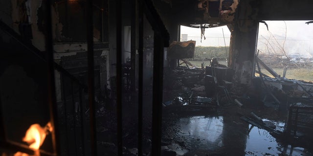A burnt house lays flooded as leftover flames from the Tick Fire continue to burn in the Santa Clarita, Calif. on Thursday. (AP Photo/ Christian Monterrosa)