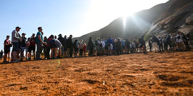 Tourists line up waiting to climb the sandstone monolith called Uluru that dominates Australia's arid center at Uluru-Kata Tjuta National Park, Friday, Oct. 25, 2019, the last day climbing is allowed.