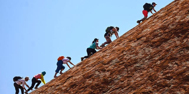 Tourists climb the sandstone monolith called Uluru that dominates Australia's arid center at Uluru-Kata Tjuta National Park, Friday, Oct. 25, 2019, the last day climbing is allowed.