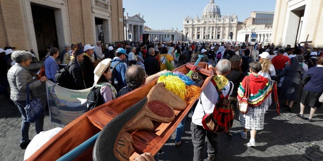 Members of Amazon indigenous populations walk during a Via Crucis, or Way of the Cross, procession to the Vatican. In foreground is a wooden statue portraying a naked pregnant woman. (AP Photo/Andrew Medichini)