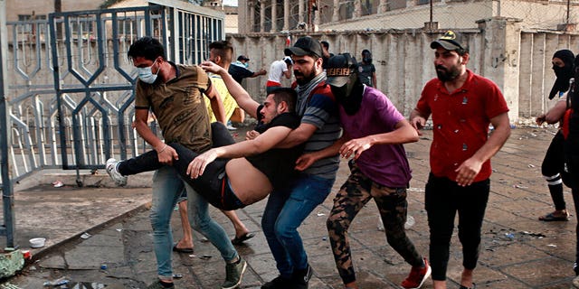 An injured protestor is rushed to a hospital during a demonstration in central Baghdad. Iraqi police fired live shots into the air as well as rubber bullets and dozens of tear gas canisters on Friday to disperse thousands of protesters