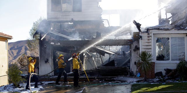 Firefighters try to put out a residence fire caused by a wildfire Friday, Oct. 25, 2019, in Santa Clarita, Calif. An estimated 50,000 people were under evacuation orders in the Santa Clarita area north of Los Angeles as hot, dry Santa Ana winds howling at up to 50 mph (80 kph) drove the flames into neighborhoods(AP Photo/Marcio Jose Sanchez)