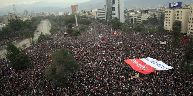 People gather during an anti-government protest in Santiago, Chile, Friday, Oct. 25, 2019. At least 19 people have died in the turmoil that has swept the South American nation. The unrest began as a protest over a 4-cent increase in subway fares and soon morphed into a larger movement over growing inequality in one of Latin America's wealthiest countries. (AP Photo/Rodrigo Abd)