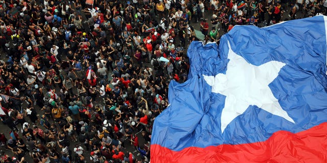 People gather during an anti-government protest in Santiago, Chile, Friday, Oct. 25, 2019. At least 19 people have died in the turmoil that has swept the South American nation. The unrest began as a protest over a 4-cent increase in subway fares and soon morphed into a larger movement over growing inequality in one of Latin America's wealthiest countries. (AP Photo/Rodrigo Abd)