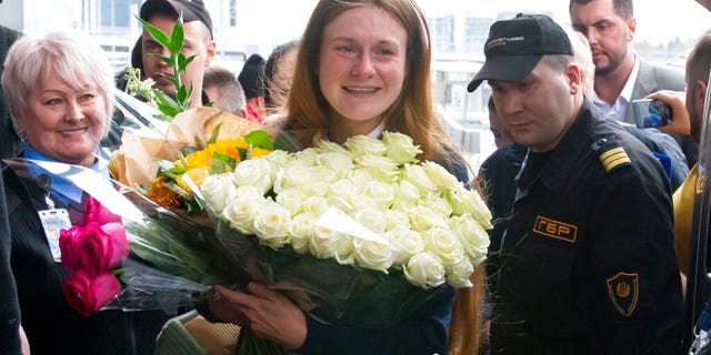 Russian agent Maria Butina, center, holds a bunch of flowers upon her arrival from the United States at Moscow International Airport Sheremetyevo outside Moscow.