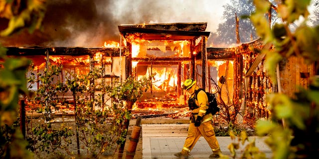 Woodbridge firefighter Joe Zurilgen passing a burning home as the Kincade Fire raged in Healdsburg, Calif., on Sunday.