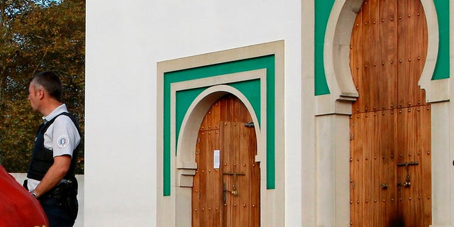 A police officer stands next to the entrance a mosque after an incident in Bayonne, southwestern France on Monday. French authorities say a suspect has been arrested for allegedly shooting and seriously injuring two elderly men who caught him trying to set fire to a mosque's door. (AP Photo/Str)