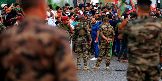 Iraqi security forces stand guard while anti-government protesters gather near Basra provincial council building during a demonstration in Basra, Iraq, Monday, Oct. 28, 2019.