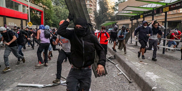 Anti-government protesters run from police in Santiago, Chile, Tuesday, Oct. 29, 2019.