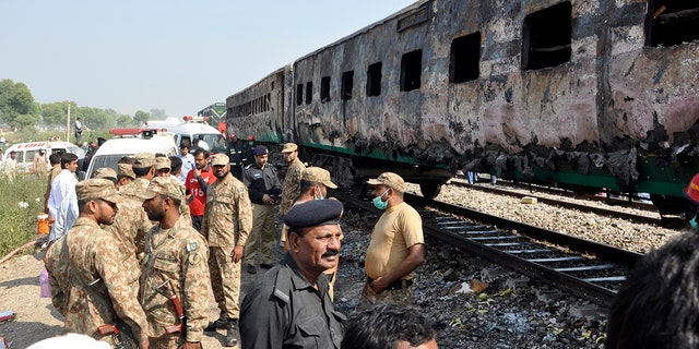 Pakistani soldiers and officials examine a train damaged by a fire in Liaquatpur, Pakistan, Thursday, Oct. 31, 2019. A massive fire engulfed three carriages of the train traveling in the country's eastern Punjab province (AP Photo/Siddique Baluch)