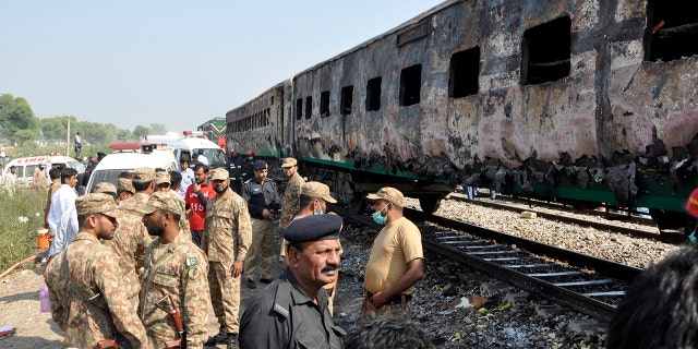 Pakistani soldiers and officials examine a train damaged by a fire in Liaquatpur, Pakistan, Thursday, Oct. 31, 2019. A massive fire engulfed three carriages of the train traveling in the country's eastern Punjab province (AP Photo/Siddique Baluch)