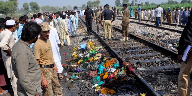 Pakistani soldiers and officials examine a train damaged by a fire in Liaquatpur, Pakistan, Thursday, Oct. 31, 2019. A massive fire engulfed three carriages of the train traveling in the country's eastern Punjab province