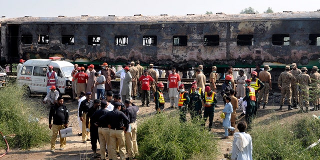 Pakistani soldiers and officials examine a train damaged by a fire in Liaquatpur, Pakistan, Thursday, Oct. 31, 2019. A massive fire engulfed three carriages of the train traveling in the country's eastern Punjab province
