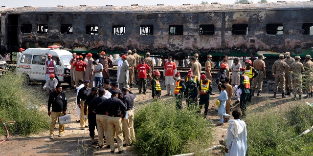 Pakistani soldiers and officials examine a train damaged by a fire in Liaquatpur, Pakistan, Thursday, Oct. 31, 2019. A massive fire engulfed three carriages of the train traveling in the country's eastern Punjab province