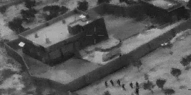 This image from video released by the Department of Defense on Wednesday, Oct. 30, 2019, and displayed at a Pentagon briefing, shows U.S. Special Forces, figures at lower right, moving toward compound of Islamic State leader Abu Bakr al-Baghdadi on Saturday, Oct. 26, 2019. (Department of Defense via AP)