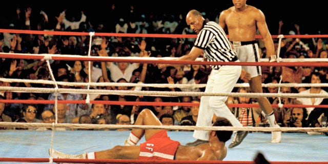 This is a Oct. 30, 1974 file photo of Muhammad Ali, right, as he stands back as referee Zack Clayton calls the count over opponent George Foreman, red shorts, in Kinshasa, Zaire. (AP Photo, File)