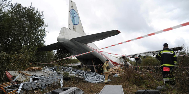 Members of emergency services work at the site of the Antonov-12 cargo airplane emergency landing in Lviv region, Ukraine Oct. 4, 2019.