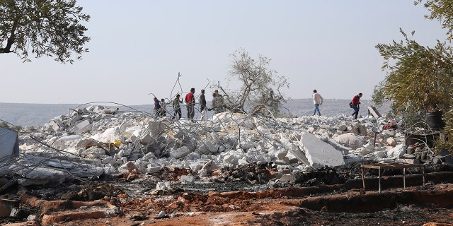 People look at destroyed houses near the village of Barisha, in Idlib province, Syria, Sunday, after an operation by the U.S. military which targeted Abu Bakr al-Baghdadi,